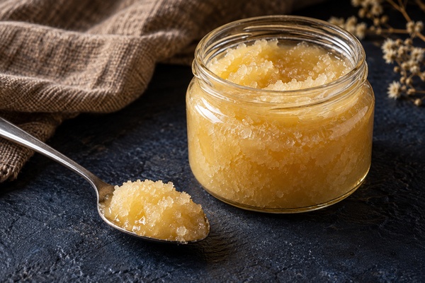 Pot de miel cristallisé à la texture granuleuse avec une cuillère