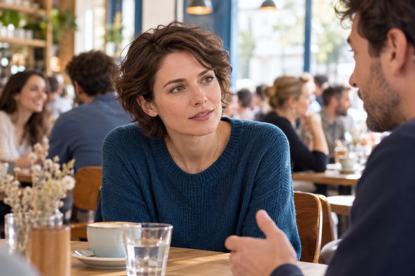 Une femme se concentre pour suivre une conversation dans un café animé